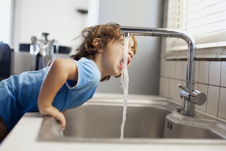 کودک در حال آب خوردن از شیر آب